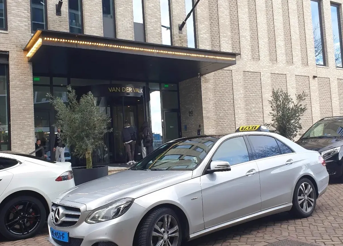 Taxi van Rogis voor de ingang van een hotel met restaurant